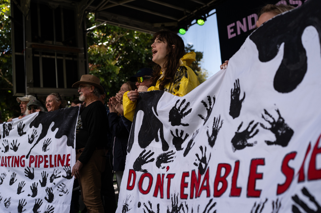 Activists opposing Sable Offshore Corp.'s offshore oil operations hold banners during the Santa Barbara Earth Day Festival in Santa Barbara, Calif., Sunday, April 26, 2026. (AP Photo/Jae C. Hong)
