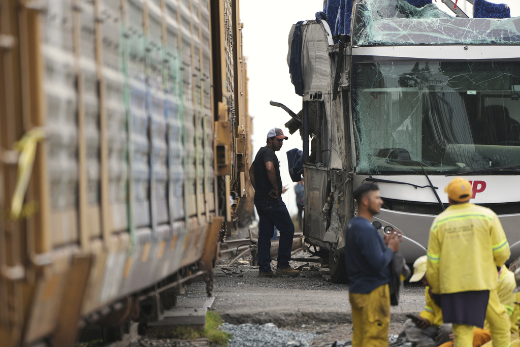 A man stands next to a bus that was hit by a freight train in Atlacomulco, Mexico, Monday, Sept. 8, 2025. (AP Photo/Fernando Llano)