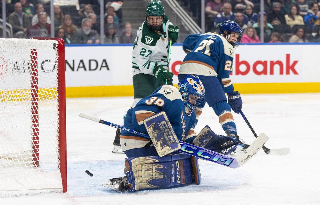 Boston Fleet's Shay Maloney (27) and Vancouver Goldeneyes' Ashton Bell (21) battle in front as the puck goes in the net past goalie Emerance Maschmeyer (38) during second period PWHL hockey action in Edmonton on Tuesday, April 7, 2026. (Jason Franson/The Canadian Press via AP)