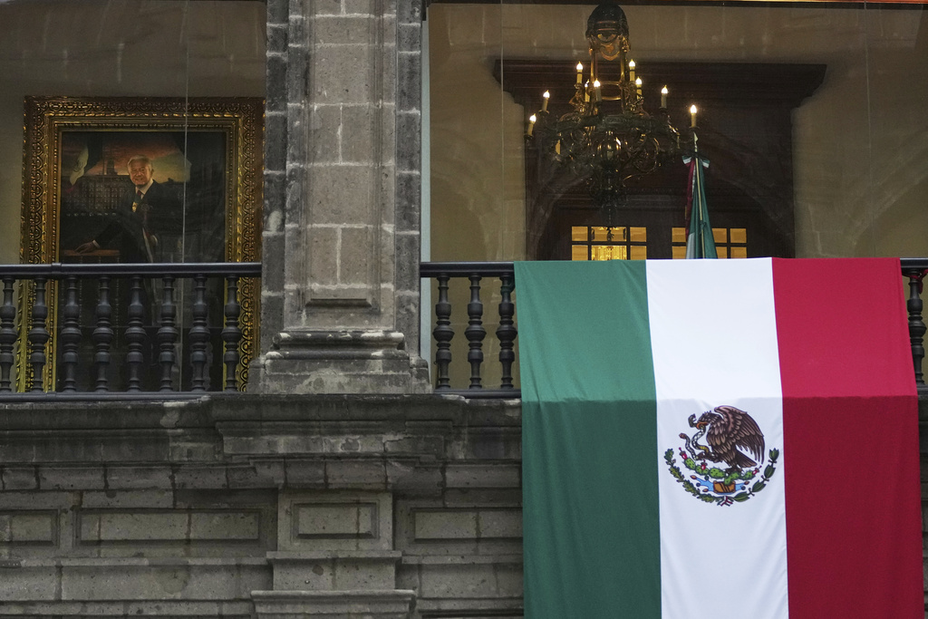 A Mexican flag hangs at the National Palace, where a portrait of former Mexico President Andres Manuel Lopez Obrador hangs, as President Claudia Sheinbaum delivers her first state-of-the-nation address in Mexico City, Monday, Sept. 1, 2025. (AP Photo/Eduardo Verdugo)