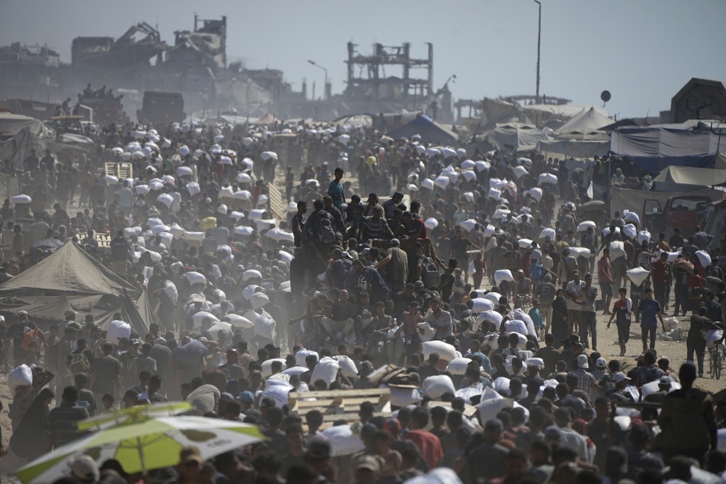 Palestinians carry sacks of flour taken from a humanitarian aid convoy in the outskirts of Beit Lahiya, northern Gaza Strip, Aug. 1, 2025. (AP Photo/Jehad Alshrafi)