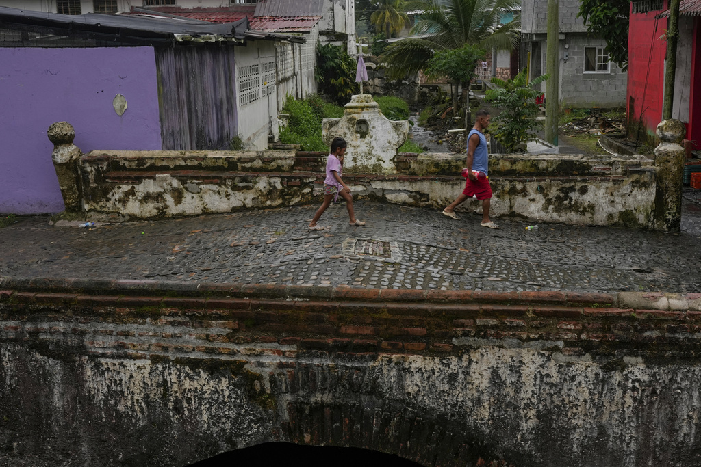 Residents cross a colonial-era bridge in Portobelo, a town on Panama's Caribbean coast that was once a key port where Spanish treasure fleets loaded silver and gold for shipment to Europe, Thursday, Aug. 14, 2025. (AP Photo/Matias Delacroix)