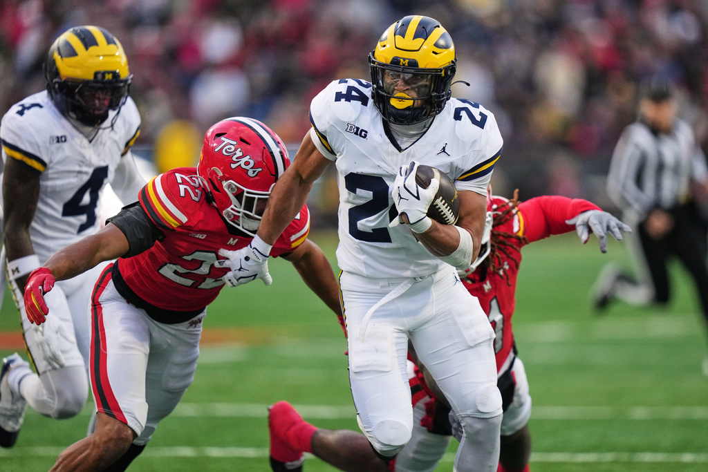 Michigan running back Bryson Kuzdzal (24) runs the ball past Maryland defensive back Jalen Huskey (22) and linebacker Daniel Wingate (1) during the first half of an NCAA college football game, Saturday, Nov. 22, 2025, in College Park, Md. (AP Photo/Stephanie Scarbrough)