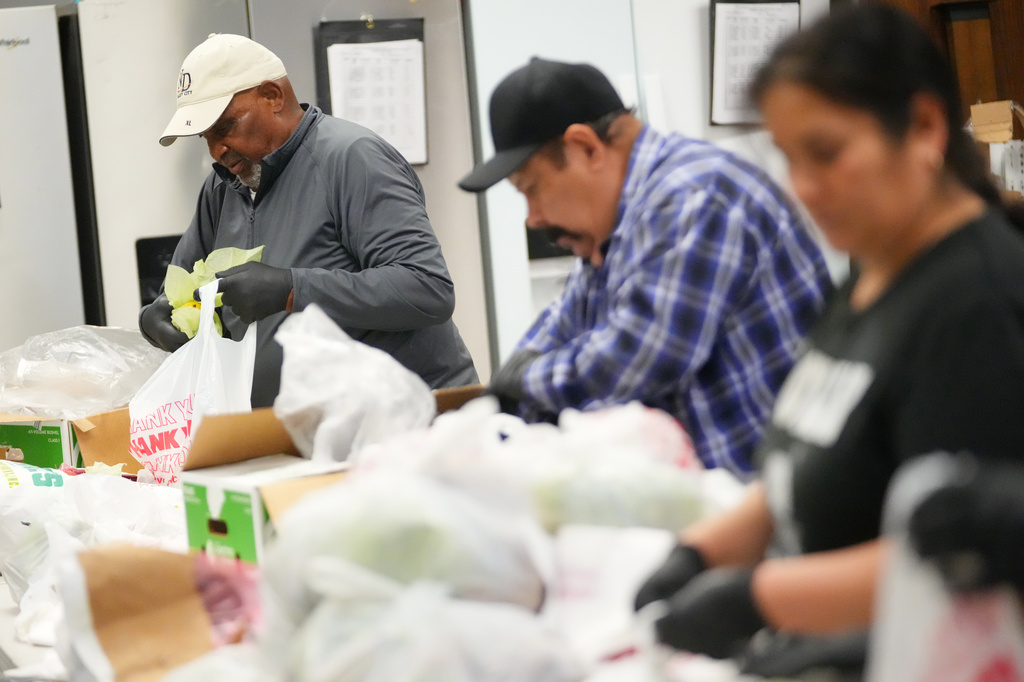 Lawrence Hall, left, a volunteer at Miles of Freedom, a Dallas-based group that provides help for individuals after they have been released from prison, whether they are on parole or are exonerees, fills grocery bags at the organization's soup kitchen Tuesday, April 21, 2026 in Dallas. (AP Photo/Julio Cortez)