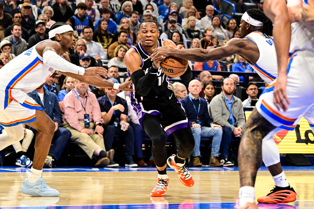 Sacramento Kings guard Russell Westbrook (18) drives against Oklahoma City Thunder guard Luguentz Dort (5) during the first half of an NBA basketball game between Sacramento Kings and Oklahoma City Thunder, Tuesday, Oct. 28, 2025, in Oklahoma City. (AP Photo/Gerald Leong)