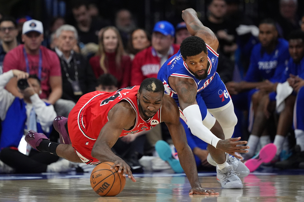 Chicago Bulls' Patrick Williams, left, and Philadelphia 76ers' Paul George chase a loose ball during the first half of an NBA basketball game Wednesday, March 25, 2026, in Philadelphia. (AP Photo/Matt Slocum)
