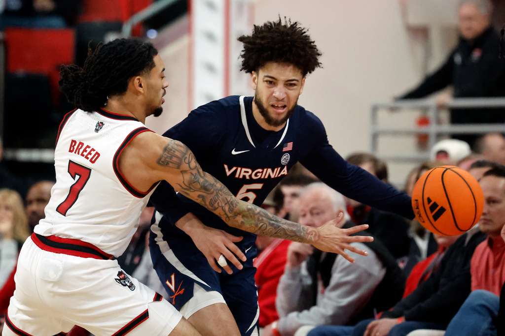 Virginia's Sam Lewis (5) moves the ball around North Carolina State's Alyn Breed (7) during the first half of an NCAA college basketball game in Raleigh, N.C., Saturday, Jan. 3, 2026. (AP Photo/Karl DeBlaker)