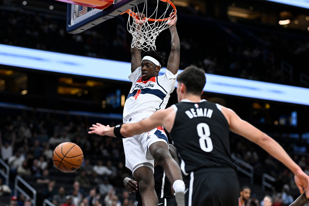 Washington Wizards forward AJ Dybantsa hangs on the rim after dunking the ball during the first half of a preseason NBA basketball game against the Brooklyn Nets in Washington, Monday, Oct. 12, 2026. (AP Photo/Terrance Williams)