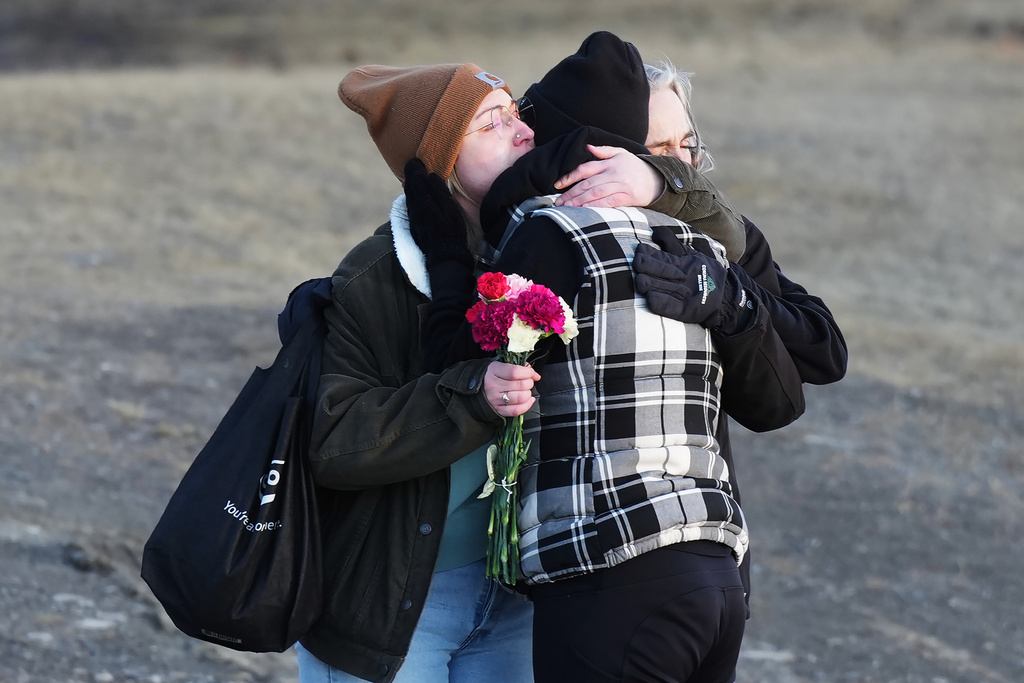 People comfort each other at a vigil for the victims of a mass shooting, in Tumbler Ridge, B.C., Friday, Feb. 13, 2026. (Christinne Muschi/The Canadian Press via AP)