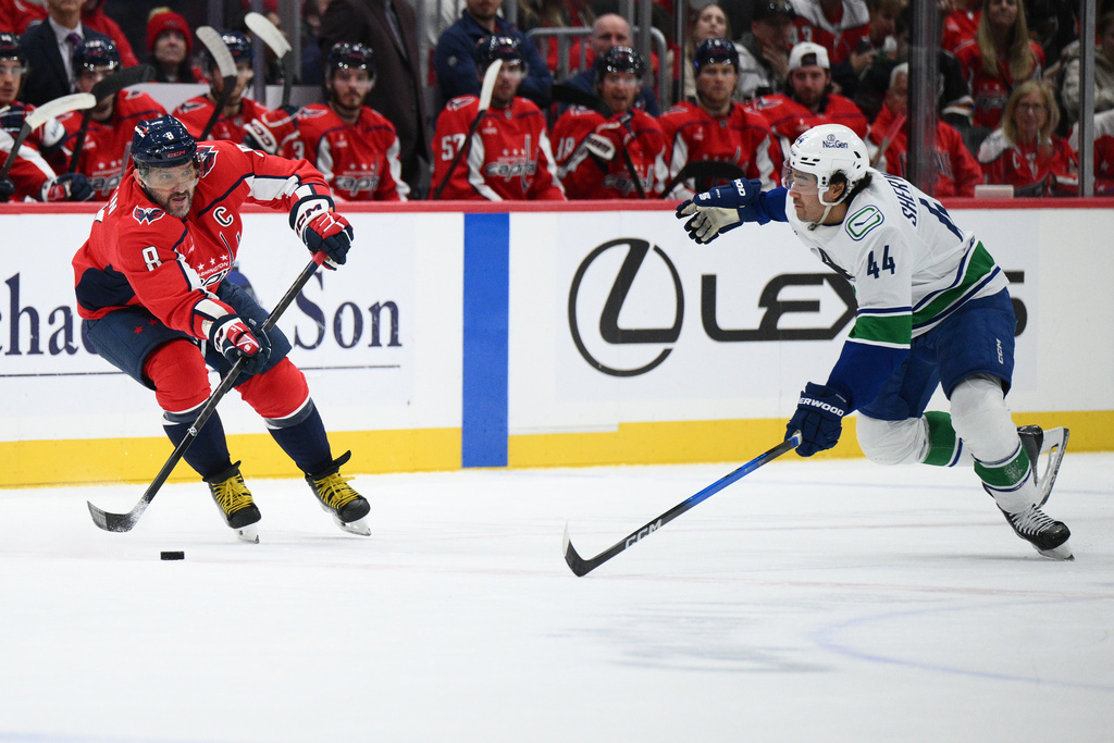 Washington Capitals left wing Alex Ovechkin (8) passes the puck against Vancouver Canucks left wing Kiefer Sherwood (44) during the first period of an NHL hockey game, Sunday, Oct. 19, 2025, in Washington. (AP Photo/Nick Wass)
