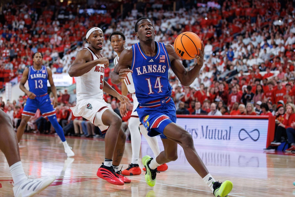 Kansas's Melvin Council Jr. (14) drives past North Carolina State's Tre Holloman (5) during the second half of an NCAA college basketball game in Raleigh, N.C., Saturday, Dec. 13, 2025. (AP Photo/Ben McKeown)