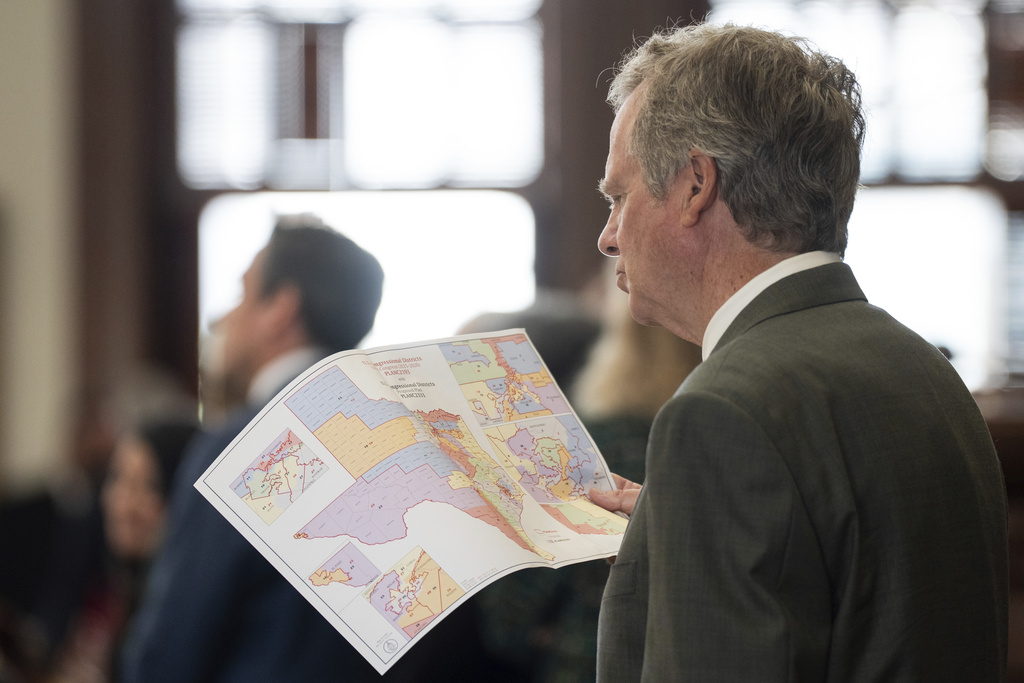 Rep. Mike Olcott, R-Fort Worth, looks at a redrawn congressional district map as its proposal is debated in the House Chamber at the Texas Capitol in Austin, Texas, Wednesday, Aug. 20, 2025. (Mikala Compton/Austin American-Statesman via AP)