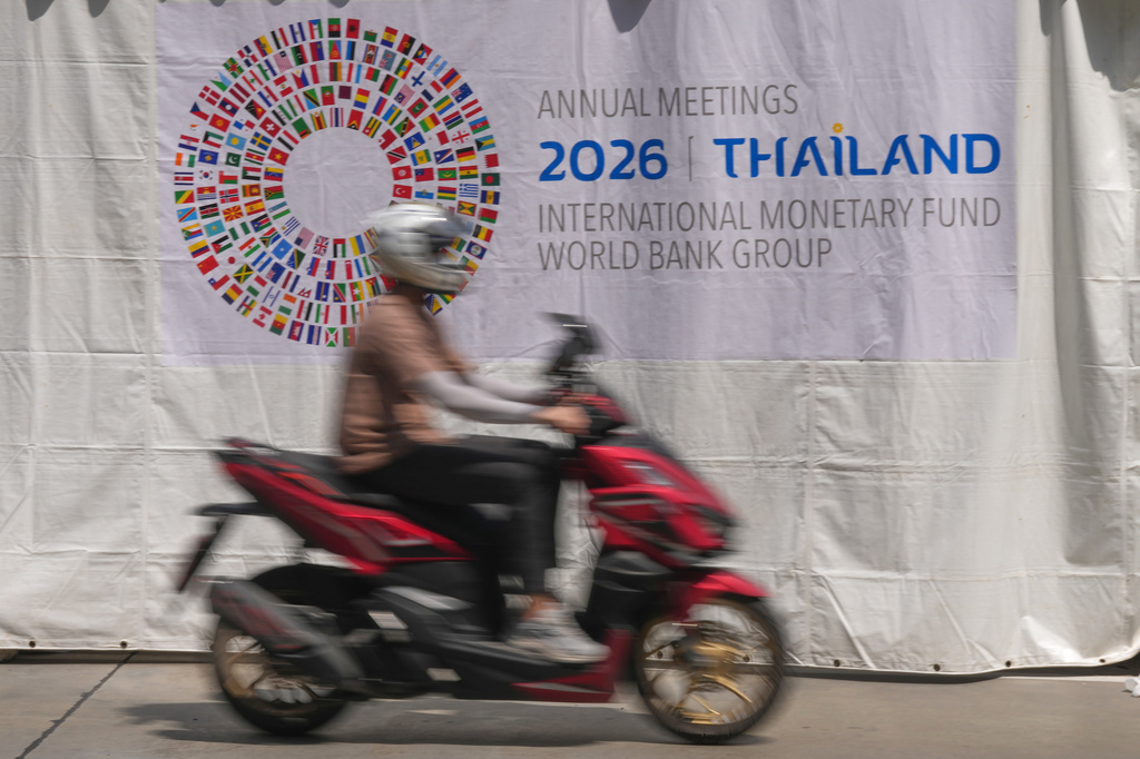 A motorcycle taxi rides past a banner at the Queen Sirikit National Convention Center ahead of the annual meetings of the International Monetary Fund (IMF) and the World Bank Group in Bangkok, Thailand, Friday, Oct. 9, 2026. (AP Photo/Sakchai Lalit)