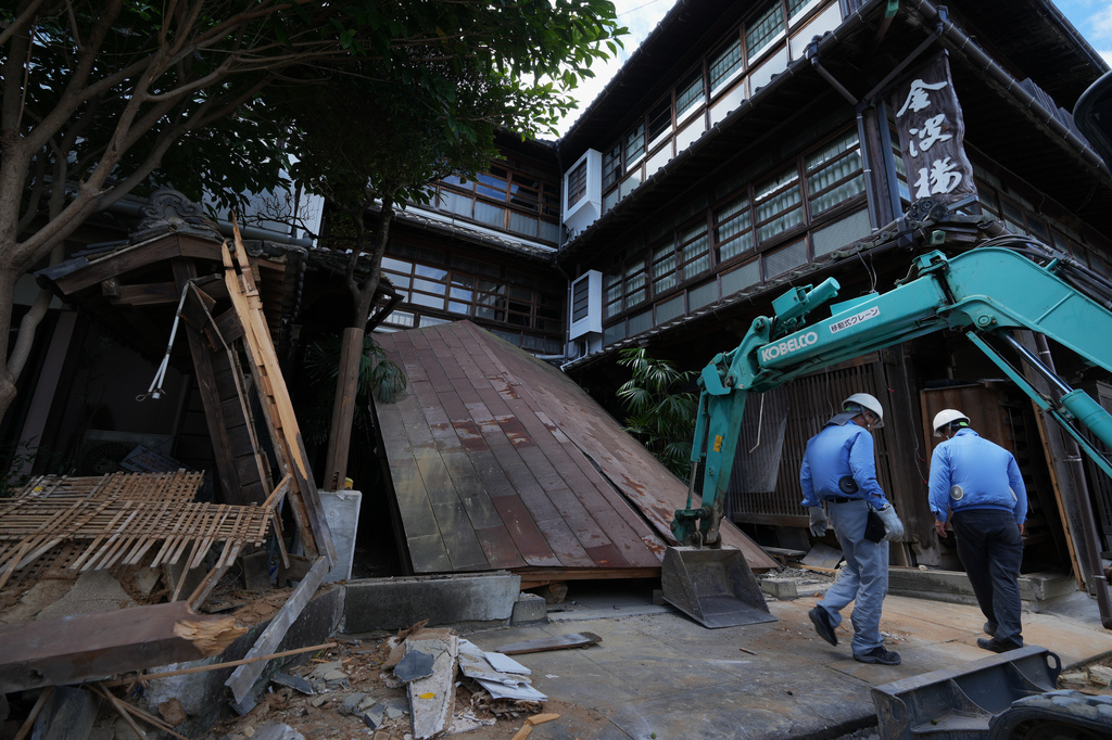 Workers inspect debris of the Kinparo inn, founded in 1910, for conservation of a possible rebuilding in Yatsushiro, southern Japan, Friday, July 31, 2026, three days after an earthquake hit the area. (AP Photo/Hiro Komae)