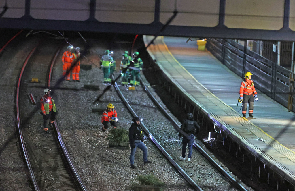 Emergency responders on the tracks by the train at Huntingdon station after a mass stabbing on a London-bound train in eastern England, in Cambridgeshire, England, Saturday, Nov. 1, 2025. (Chris Radburn/PA via AP)