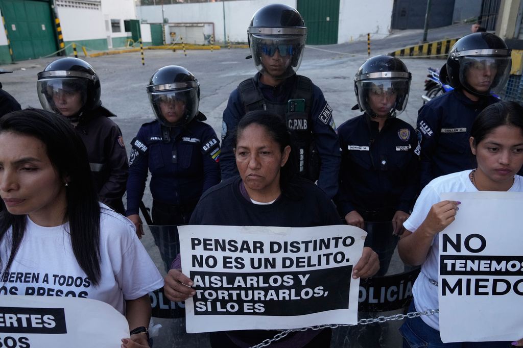 Nelcy Escorcia, center, holds a sign with a message reading in Spanish; “Thinking differently isn’t a crime; isolating and torturing them is”, during a protest outside a detention center where her husband, Franklin Parra, is being held on political grounds, in Caracas, Venezuela, Thursday, Feb. 12, 2026. (AP Photo/Ariana Cubillos)