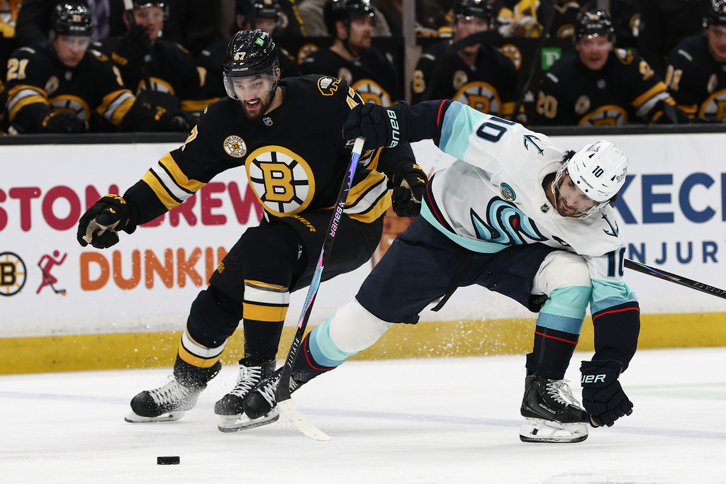 Boston Bruins' Mark Kastelic eyes a loose puck as he gets past Seattle Kraken's Matty Beniers during the second period of an NHL hockey game Thursday, Jan. 15, 2026, in Boston. (AP Photo/Winslow Townson)
