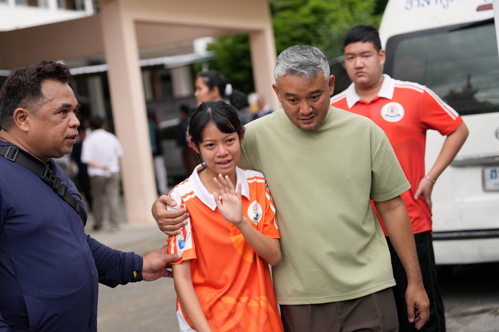 A student is guided away from the scene after a shooting at the Debsirin Nonthaburi School in Thailand's Nonthaburi province, Friday, Aug. 7, 2026. (AP Photo/Sakchai Lalit)