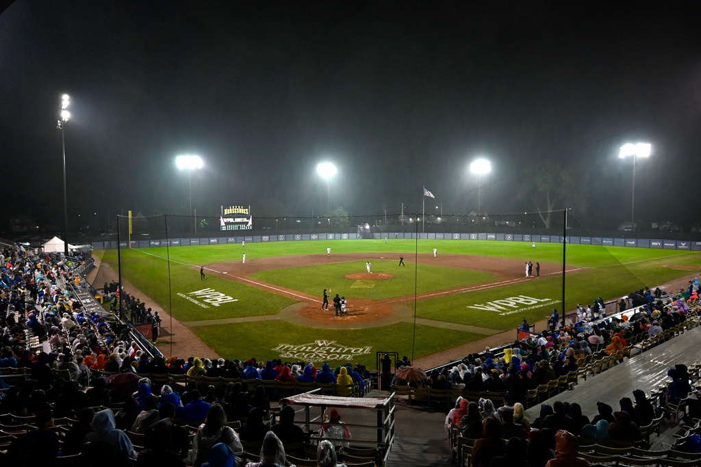 The crowd sits in the rain during the seventh inning of the inaugural Women's Professional Baseball League game between the Los Angeles Queens and the New York Heights, Saturday, Aug. 1, 2026, in Springfield, Ill. (AP Photo/Lexie Knight)
