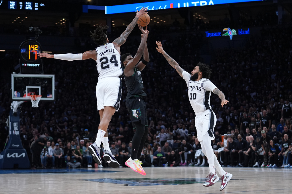 Minnesota Timberwolves guard Anthony Edwards, center, shoots against San Antonio Spurs guard Devin Vassell (24) and forward Julian Champagnie (30) during the first half of Game 6 of an NBA basketball second-round playoffs series against the San Antonio Spurs in Minneapolis, Friday, May 15, 2026. (AP Photo/Abbie Parr)