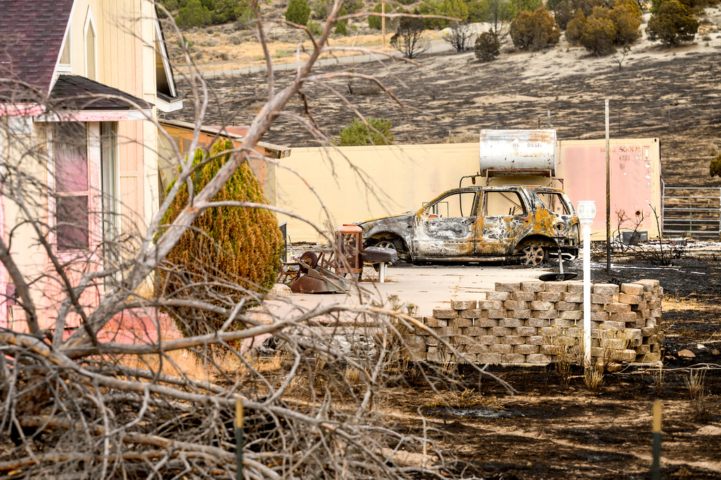 A scorched car sits outside a home that survived the Bug Fire near Reno, Nev., Thursday, Aug. 13, 2026. (AP Photo/Noah Berger)