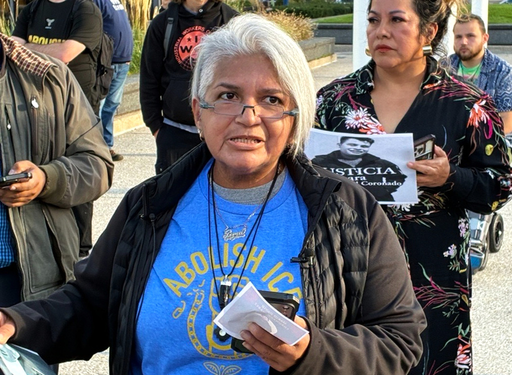 In this photo taken with a smartphone, Gema Lowe, an organizer of Movimiento Cosecha GR demands justice Thursday, Sept. 24, 2026, for Mario David Coronado Juarez, who died in a car crash while fleeing ICE officers Sunday, Sept. 20 in Grand Rapids, Ill. (John Agar/The Grand Rapids Press via AP)