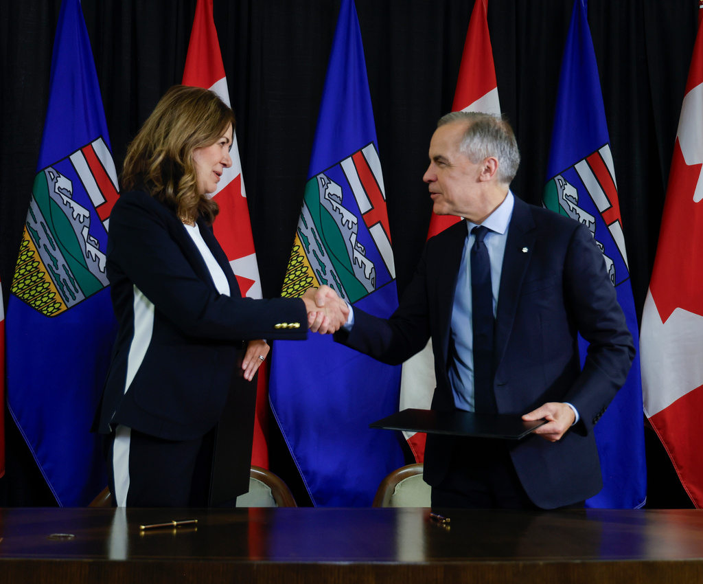 Prime Minister Mark Carney, right, signs an MOU with Alberta Premier Danielle Smith in Calgary, Alta., Thursday, Nov. 27, 2025. (Jeff McIntosh /The Canadian Press via AP)