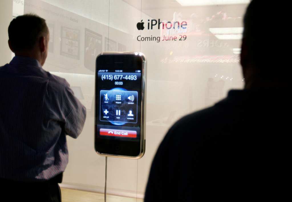 FILE - People watch an Apple iPhone advertisement outside an Apple store in Palo Alto, Calif., June 21, 2007. (AP Photo/Paul Sakuma, File)