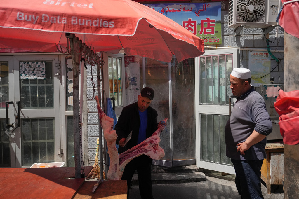 A vendor chops meat for his customer outside the Jinshan market in Altay Prefecture, northwest China's Xinjiang Uyghur Autonomous Region, Wednesday, June 10, 2026. (AP Photo/Andy Wong)