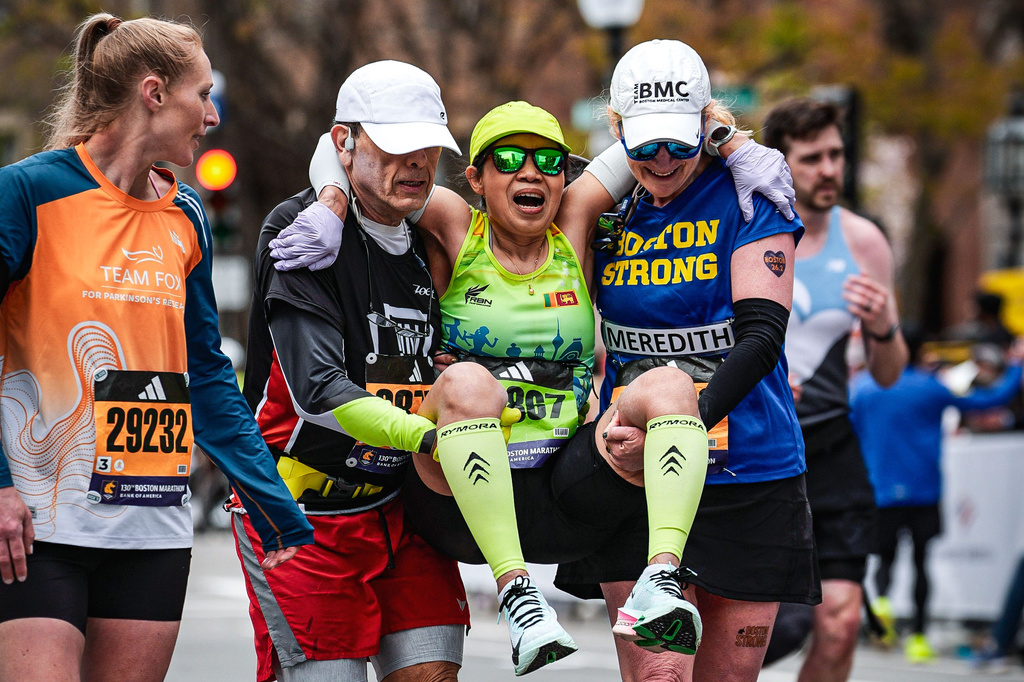 Marathon runner Jessica Kier, left, looks on as runners William Bara-Jimenez, second from left, and Meredith Rosenberg, right, help runner Lan Nguyen reach the finish line during the Boston Marathon, Monday, April 20, 2026, in Boston. (Brian Lee/Boston Athletic Association and MarathonFoto via AP Photos)