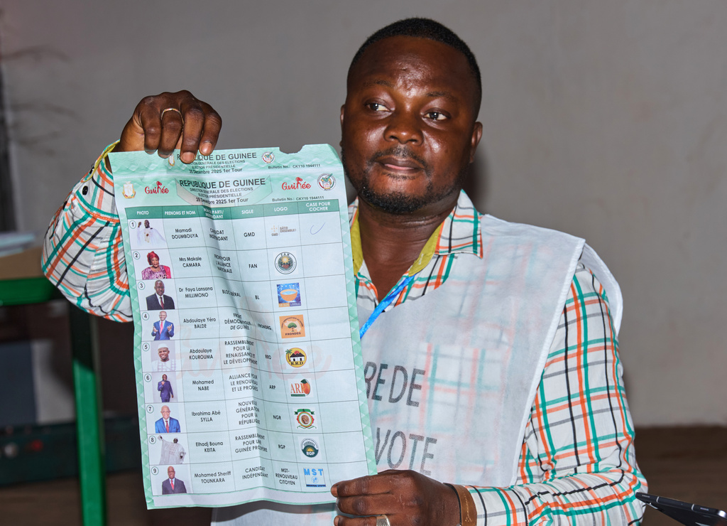 An official holds up a ballot paper at a polling station as polls close during the presidential election in Conakry, Guinea, Sunday, Dec. 28, 2025. (AP Photo/Fode Toure)
