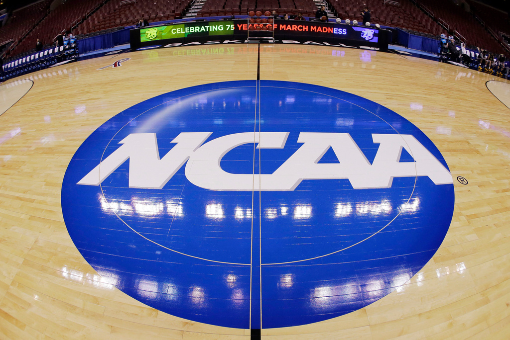 FILE - This photo taken with a fisheye lens shows the NCAA logo displayed at mid-court in Philadelphia, March 21, 2013. (AP Photo/Matt Slocum, File)