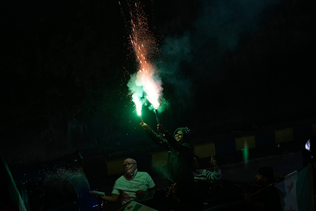 A Syrian man fires fireworks during celebrations marking the first anniversary of the ousting of the Bashar Assad regime in Damascus, Syria, Sunday, Dec. 7, 2025. (AP Photo/Hussein Malla)
