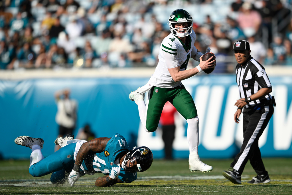 New York Jets quarterback Brady Cook (4) runs with the ball against Jacksonville Jaguars defensive end Josh Hines-Allen (41) during the second half of an NFL football game, Sunday, Dec. 14, 2025, in Jacksonville, Fla. (AP Photo/Phelan M. Ebenhack)