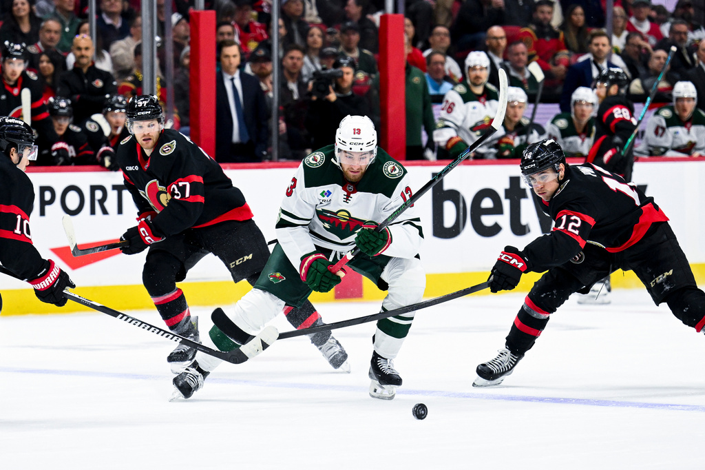 Minnesota Wild's Yakov Trenin (13) chases down the puck as Ottawa Senators' Shane Pinto (12) works to prevent a play during the first period of an NHL hockey game, Saturday, April 4, 2026, in Ottawa, Ontario. (Spencer Colby/The Canadian Press via AP)