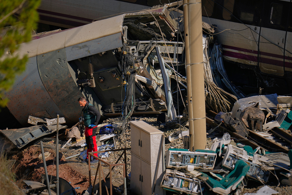 Guardia Civil officers collect evidence next to the wreckage of train cars involved in a collision in Adamuz, southern Spain, Tuesday, Jan. 20, 2026. (AP Photo/Manu Fernandez)