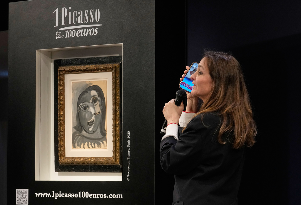 Peri Cochin, right, founder of "1 Picasso for 100 euros," speaks next to the painting 'Head of a Woman' by Pablo Picasso, painted in 1941, during the raffle draw at Christie's in Paris, Tuesday, April 14, 2026, in support of Alzheimer's research. (AP Photo/Michel Euler)