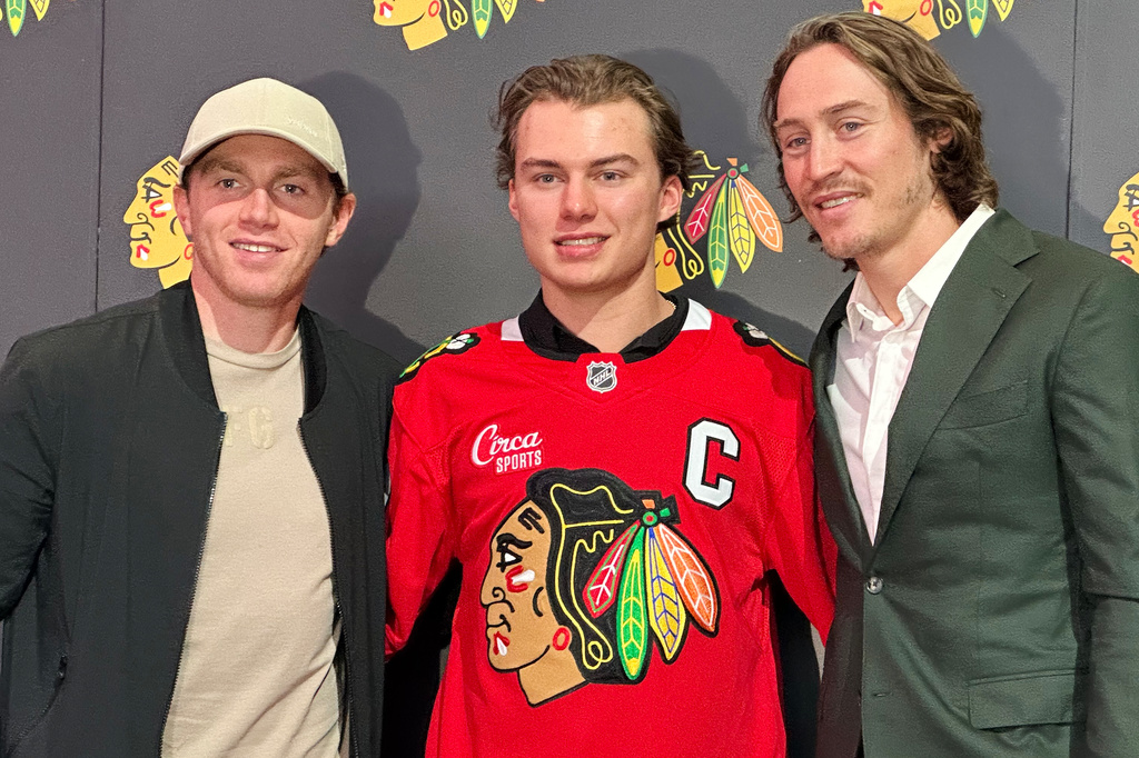 In this photo taken with a smartphono, Chicago Blackhawks players, from left, Patrick Kane, Connor Bedard and Tyler Bertuzzi pose during a news conference introducing Bedard as the new captain of the NHL hockey club, Tuesday, Sept. 15, 2026, in Chicago. (AP Photo/Jay Cohen)