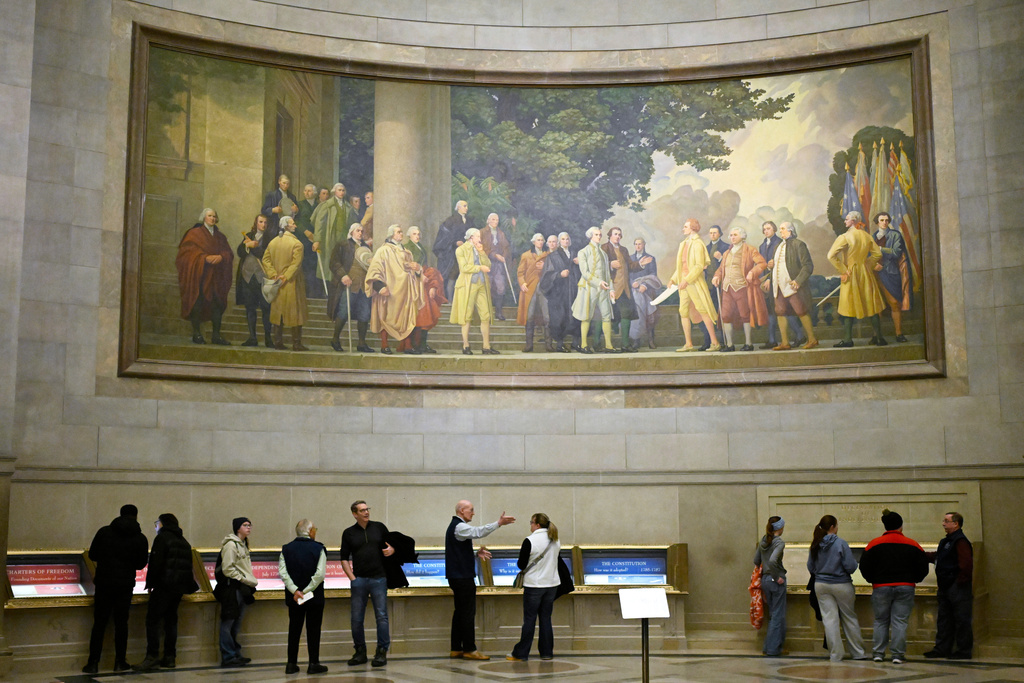 A large wall mural showing the signing of the Declaration of Independence is seen over visitors at the National Archives Thursday, Jan. 29, 2026, in Washington. (AP Photo/John McDonnell)