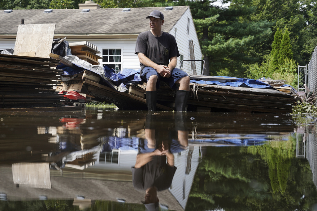 Frank Gounder sits in his flooded backyard, where his wood shop was also damaged by floodwaters, in Indianapolis, Sunday, Aug. 16, 2026. (AP Photo/Obed Lamy)
