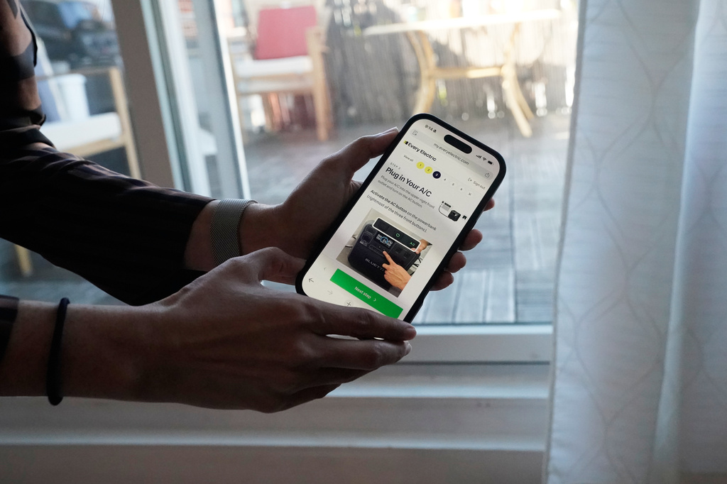 Sonam Velani shows an app that is used to plug in a battery from Every Electric to power an air conditioner as part of a pilot program with the city's energy company Con Edison to reduce pressure on the electrical grid Monday, April 27, 2026, in the Brooklyn borough of New York. (AP Photo/Alyssa Goodman)