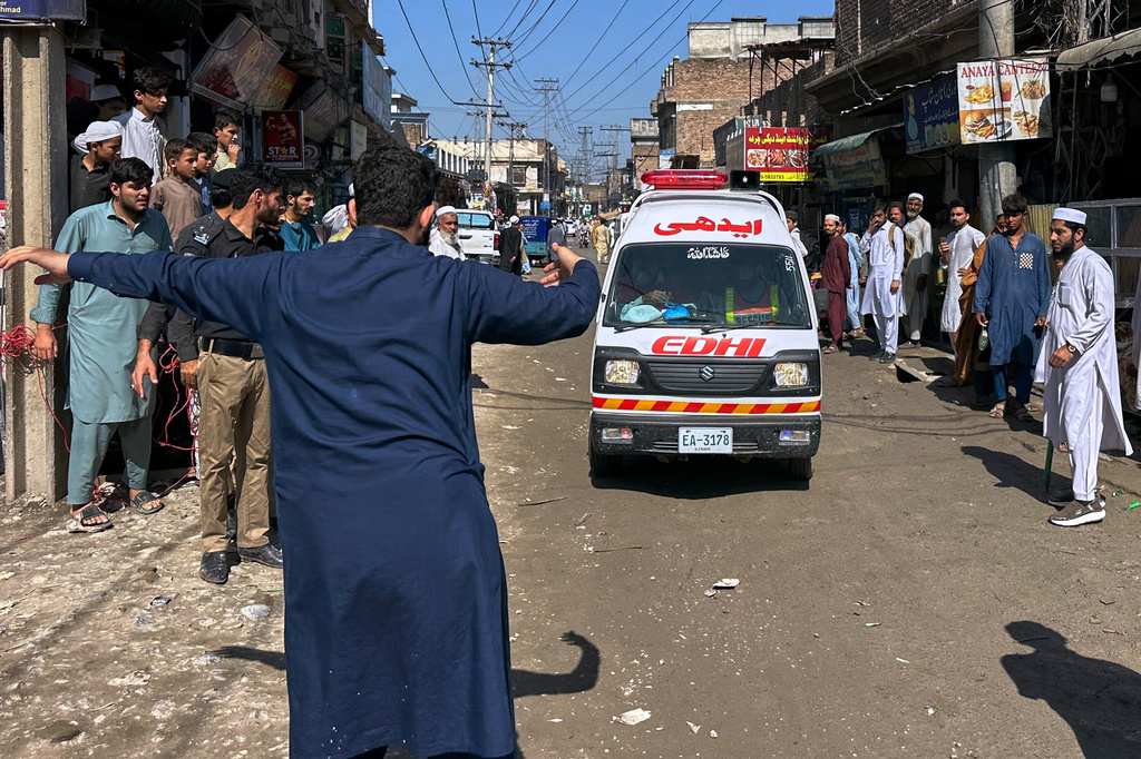 A volunteer clears the way for an ambulance transporting injured school children following a roof collapse at a private school in Peshawar, Pakistan, Thursday, Oct. 15, 2026. (AP Photo/Maaz Awan)