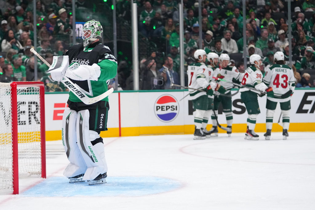 Minnesota Wild players, right, celebrate a goal by Ryan Hartman as Dallas Stars goaltender Jake Oettinger, left, stands in his crease during the second period in Game 1 of a first-round NHL Stanley Cup playoffs hockey series, Saturday, April 18, 2026, in Dallas, Texas. (AP Photo/Julio Cortez)