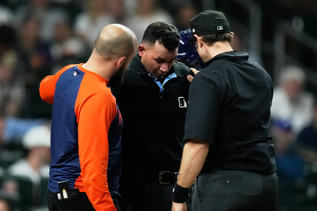 Umpire Roberto Ortiz, center, is checked out for injury before leaving the game during the sixth inning of a baseball game between the Seattle Mariners and the Houston Astros in Houston, Wednesday, May 13, 2026. (AP Photo/Ashley Landis)