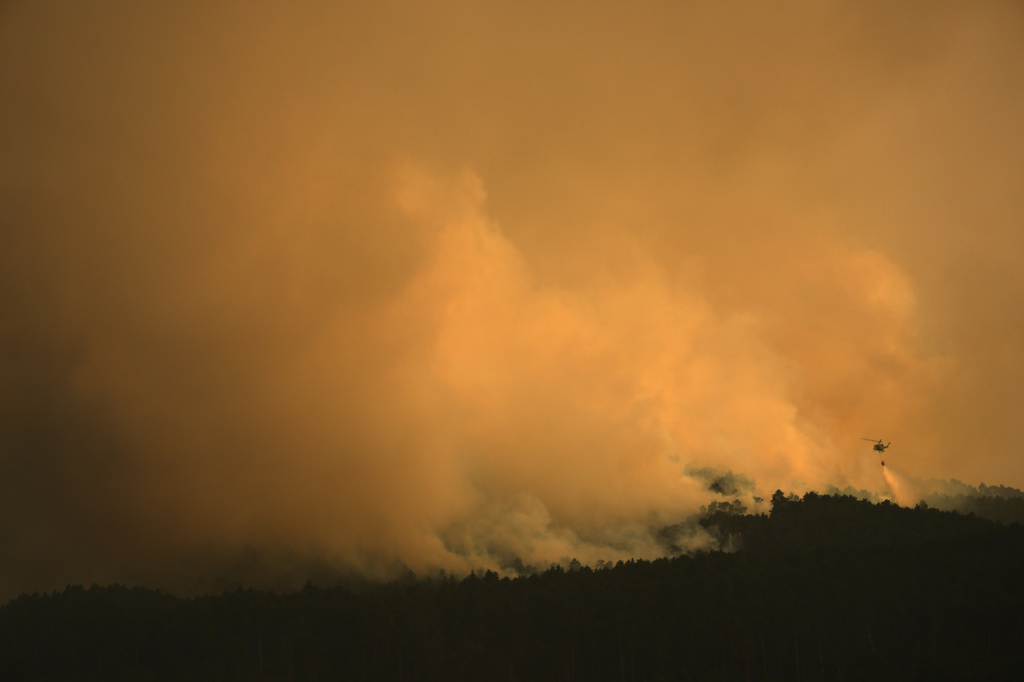 A firefighting helicopter drops water on the flames as a wildfire advances near Condemios de Arriba, Guadalajara province, Spain, Wednesday, July 22, 2026, after a wildfire scorched tens of thousands of hectares in one of Spain's largest wildfires in recent years. (AP Photo/Manu Fernandez)