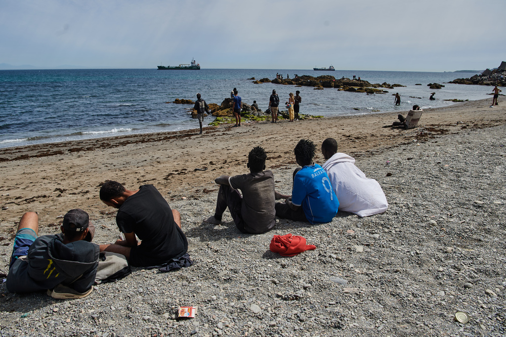 Migrants who crossed into Spain from Morocco gather on a beach in the Spanish enclave of Ceuta, Monday, Aug. 3, 2026. (AP Photo/Antonio Sempere)