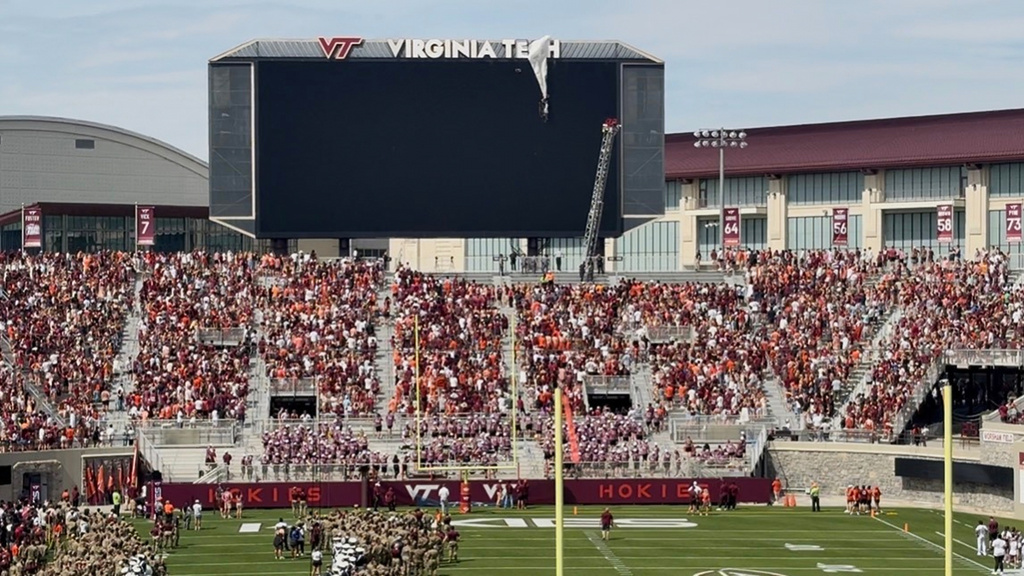 In this image from video, personnel on a lift work to secure a skydiver that crashed into the Lane Stadium scoreboard before Virginia Tech’s spring NCAA college football game, Saturday, April 18, 2026, in Blacksburg, Va. (Ben Walls/WRIC8 via AP)