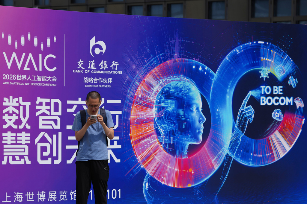 A visitor stands near a poster for the World AI Conference in Shanghai, China on July 17, 2026. (AP Photo/Ng Han Guan)