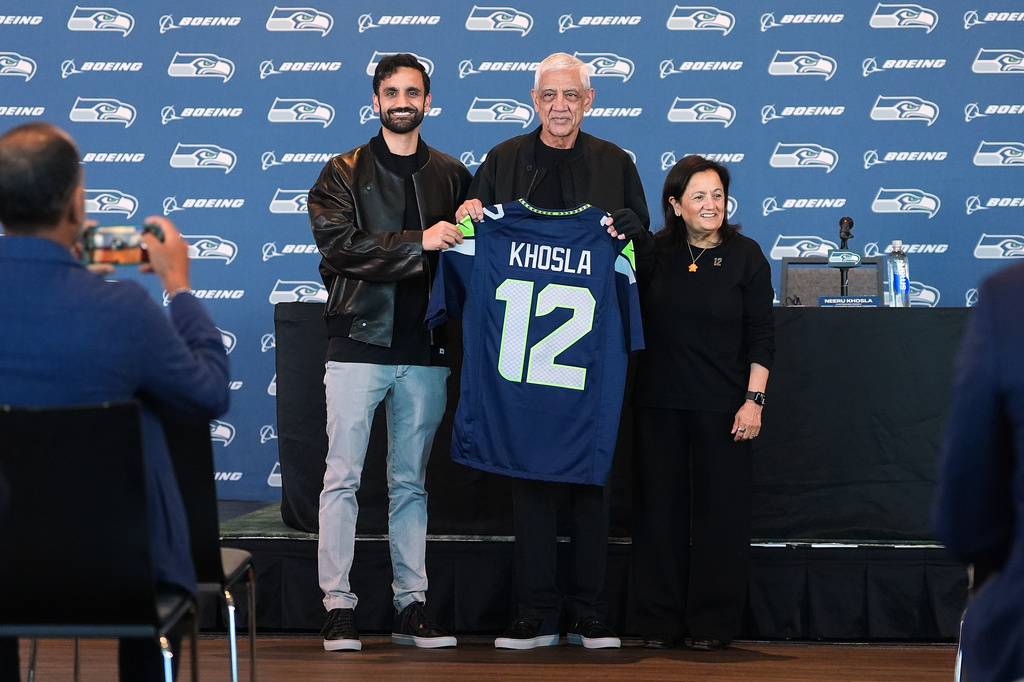Seattle Seahawks owners, from left, Vice Chair Neal Khosla, Chair Vinod Khosla and Controlling Owner &amp; President of the Seahawks Charitable Foundation Neeru Khosla pose with a Seahawks jersey before a news conference before an NFL football game between the Seahawks and the New England Patriots, Wednesday, Sept. 9, 2026, in Seattle. (AP Photo/Lindsey Wasson)