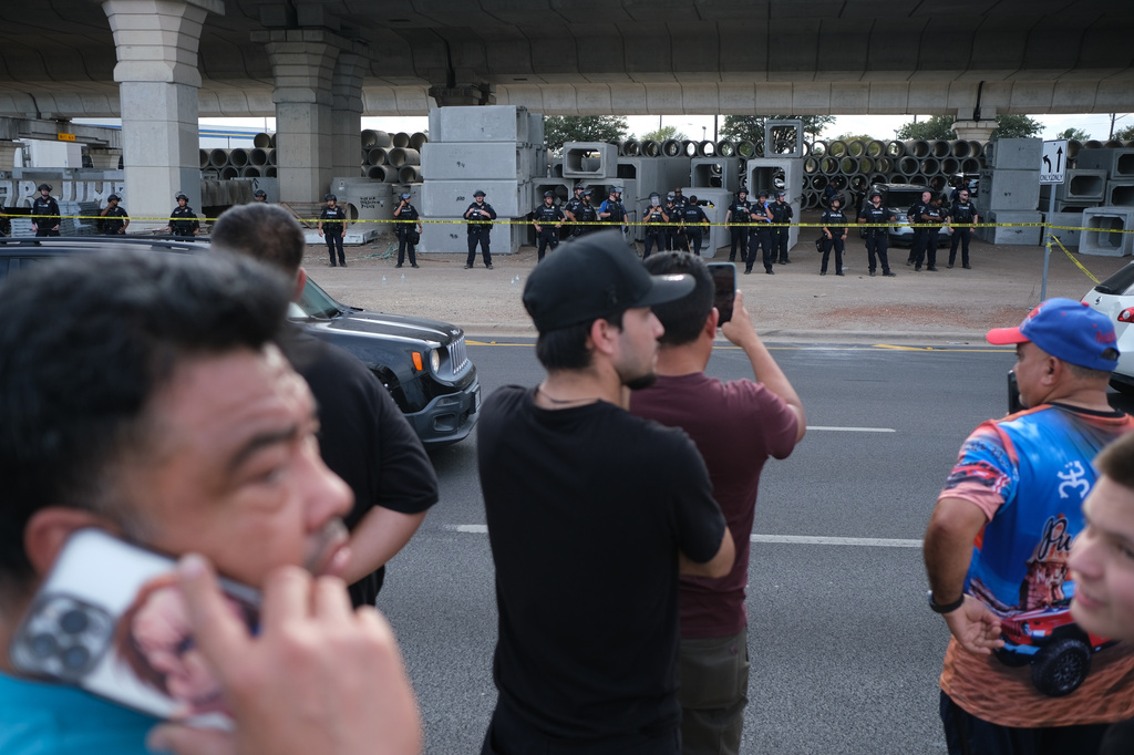 People gather where local authorities say a U.S. Immigration and Customs Enforcement officer (ICE) shot and wounded a man in Austin, Texas, Sunday, Sept. 20, 2026. (AP Photo/Joel Angel Juarez)